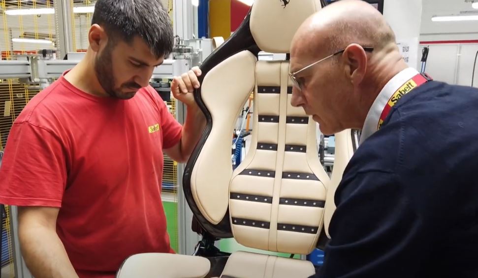 Two man inspecting a car seat with their hands